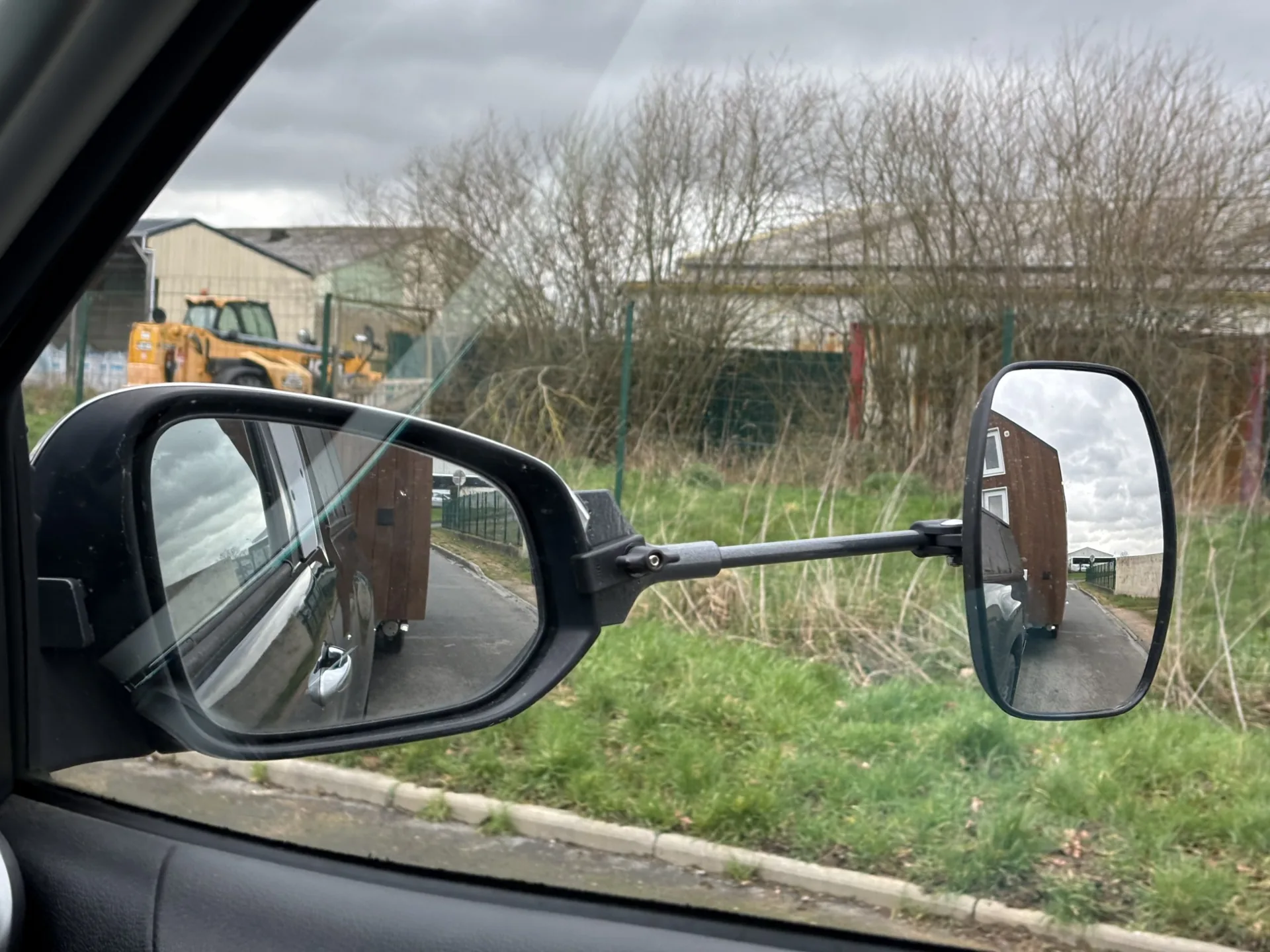 Convoi de tiny house en circulation, vu depuis le rétroviseur grand angle du véhicule tracteur